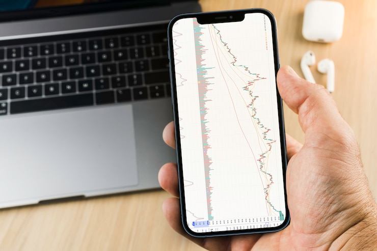 Photo financial stock market graph on the smartphone screen on wooden background with a computer beside it. stock exchange.