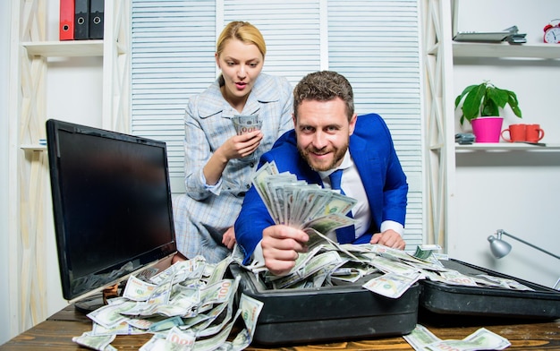 Financial success man businessman and woman secretary with pile\
dollar banknotes profit and richness concept businessman near cash\
dollars profit huge profit concept counting money profit