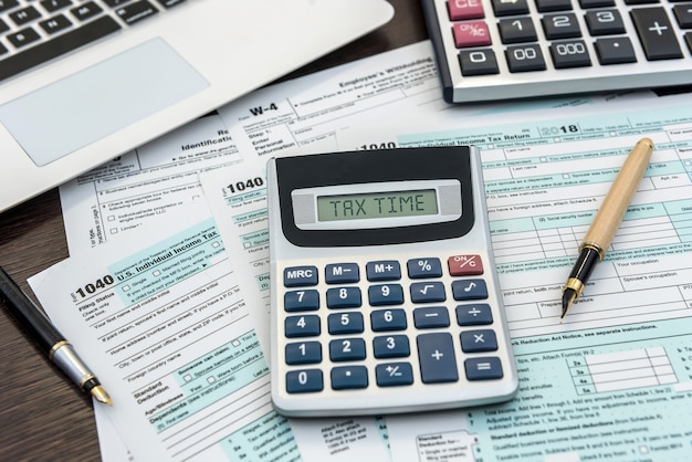financial time tax form with laptop and calculator. office paperwork. accounting