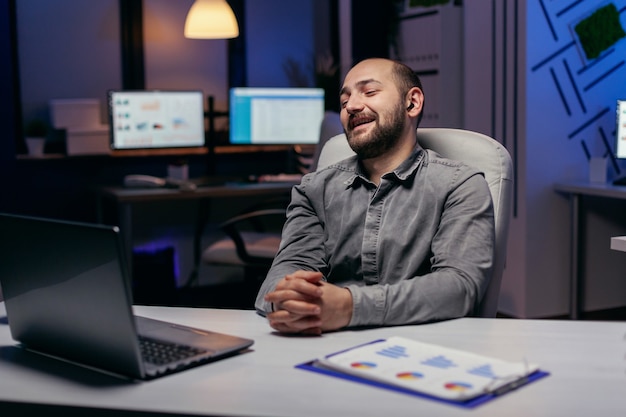 Financieel specialist die over statistieken bespreekt tijdens online gesprek met laptop en draadloze koptelefoon. Zakenman tijdens een belangrijke videoconferentie terwijl hij overwerkt op kantoor.