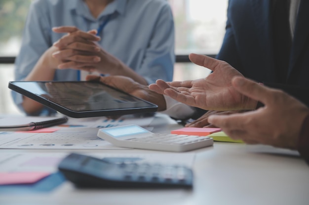 Financiële analisten analyseren zakelijke financiële rapporten over een investeringsproject voor digitale tablets tijdens een discussie tijdens een bedrijfsbijeenkomst die de resultaten van hun succesvolle teamwerk laat zien