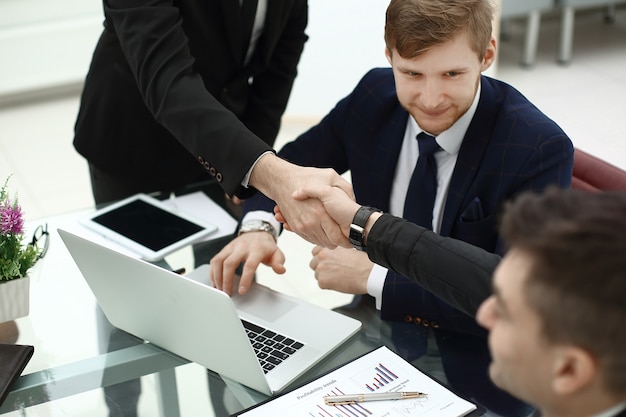 Financiële partners handdrukken over een bureau op kantoor.