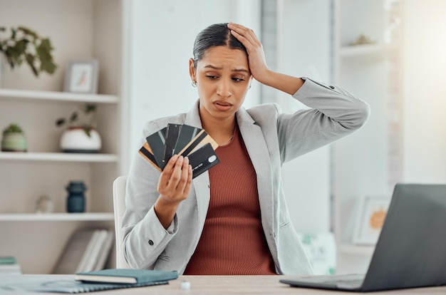 Financiële stress bezorgde en gefrustreerde vrouw met bankkaarten in haar hand aan haar bureau Zakelijke vrouw bezorgd over economische beslissingen kredietrente of lening en schulden in geldcrisis