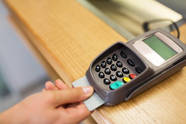 Foto financiën, geld, technologie, betalingen en mensen - close-up van de hand die een bankkaart in de terminal stopt