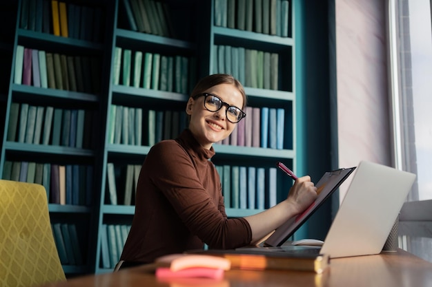 Financier vrouw die werkt in een kantoor coworking space werkplek met behulp van een laptop die een bericht schrijft