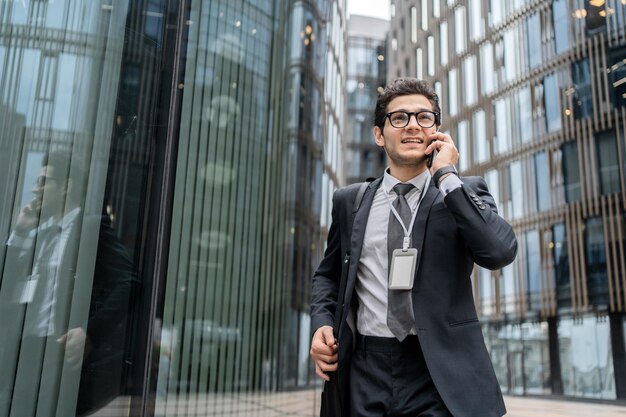 A financier with glasses a man uses a phone in his hands calls\
a colleague