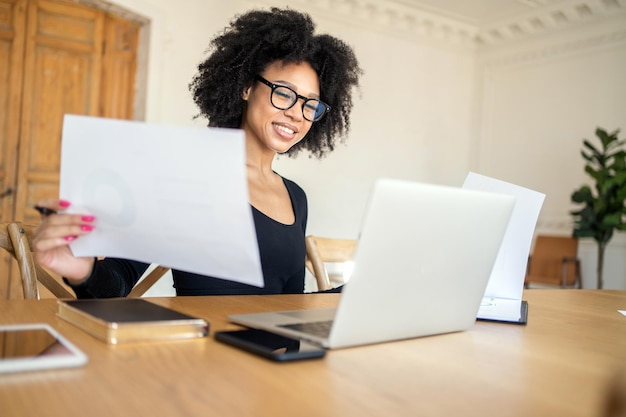 Financiervrouw die met documenten werkt in de coworking-ruimte op kantoor, videochat met een collega