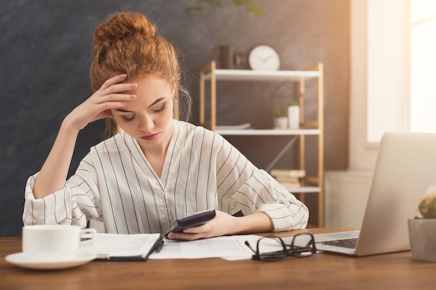 Financiervrouw in bureau die financiële rekeningen telt. Geconcentreerde vrouwelijke manager bezig met marketingstrategie op de werkplek