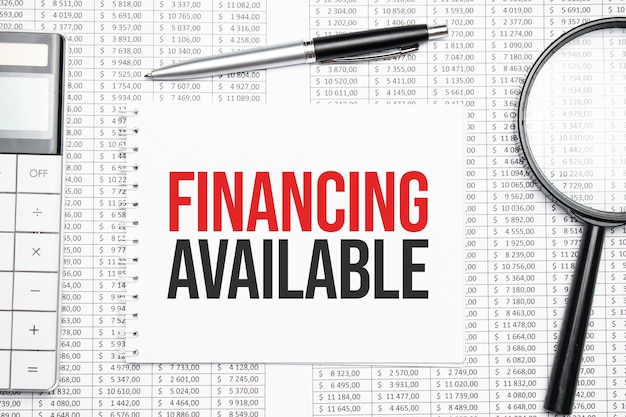 FINANCING AVAILABLE text on paper with calculator,magnifier ,pen on the graph background