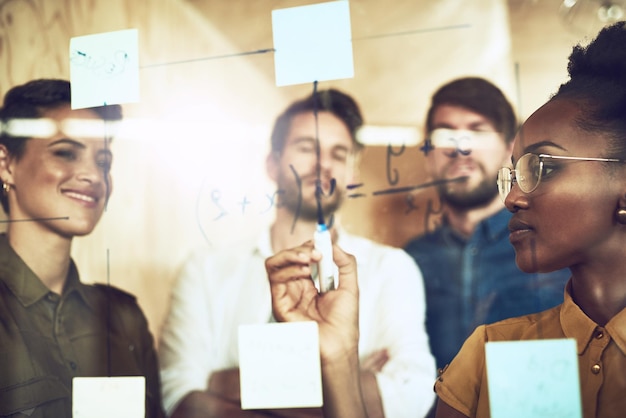 Finding solutions as a team Shot of a group of businesspeople brainstorming with notes on a glass wall