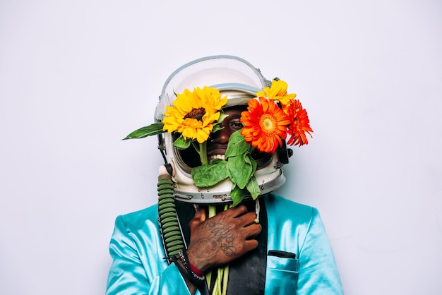 Concetto di belle arti con un uomo che indossa un casco spaziale e una composizione di fiori flowers