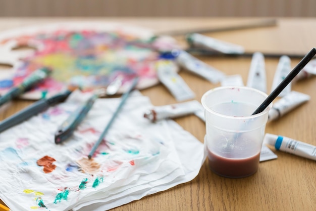 Foto creatività artistica e strumenti artistici concetto pennello immersi in una tazza d'acqua e colore su tessuto di carta