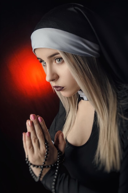 Fine art portrait of a novice nun in deep prayer with rosary