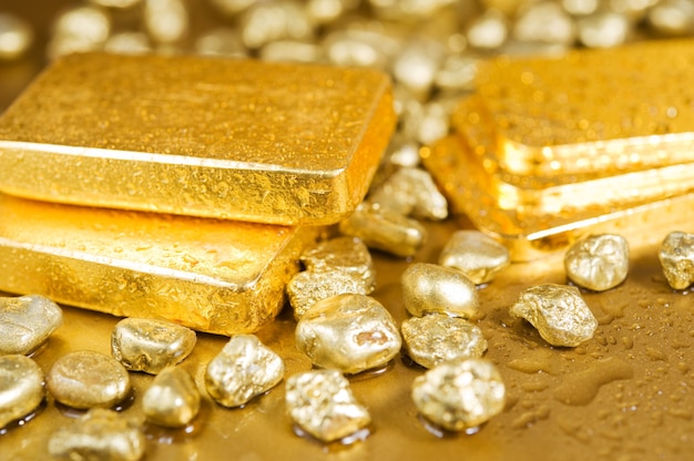 fine gold ingots and nuggets on a wet golden background