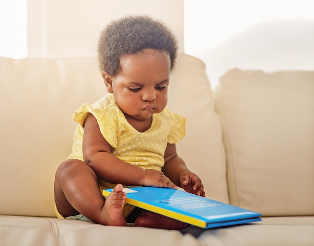 Fine Ill read it myself Full length shot of a baby girl sitting on the sofa at home