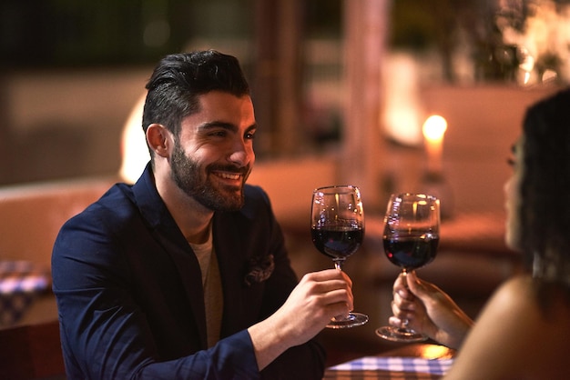 To a fine night out Shot of a cheerful young couple having a celebratory toast with wine glasses while looking into each others eyes over dinner outside at night