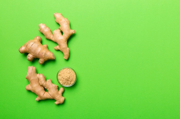 Finely dry Ginger powder in bowl with green leaves isolated on colored background top view flat lay