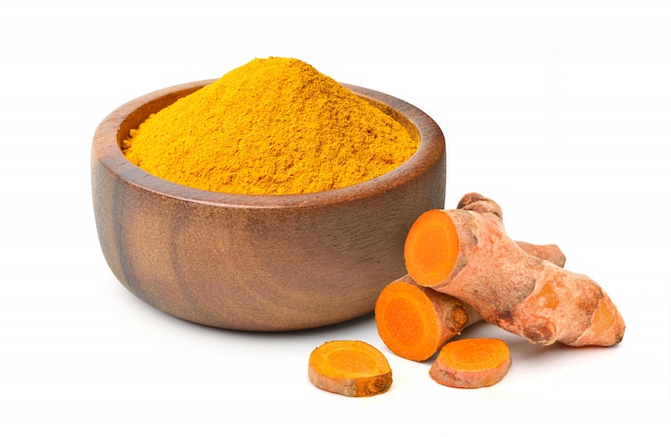Photo finely dry turmeric powder in wooden bow with  rhizome sliced isolated on white background