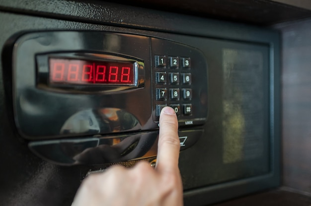 Finger are pressing the number keys of electric safe