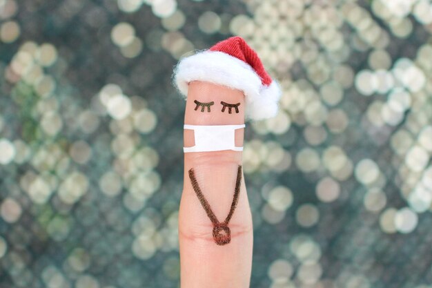 Finger art of lonely woman in medical mask from COVID-2019. Concept people celebrate Christmas in new year hat.
