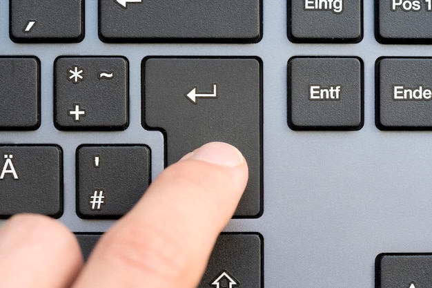 写真 優雅な近代的なデザインのキーボードでenterキーを押す瞬間の指をキャプチャー