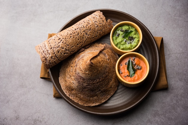 Finger millet orã‚â ragi dosaã‚â è una sana colazione indiana servita con chutney, a forma di rotolo, piatto o cono