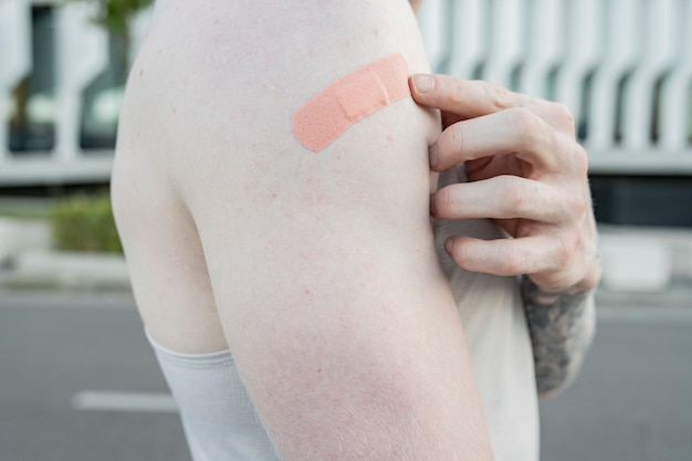 Photo finger pointing to band-aid on arm, covid-19 vaccine