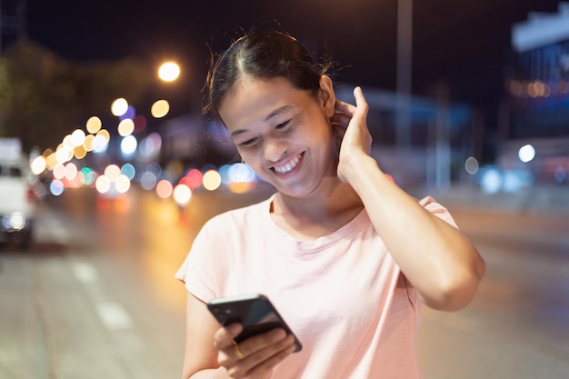 Foto dito puntato sullo schermo del telefono cellulare primo piano messaggi di testo persona che tocca smartphone notte città luce ragazza che utilizza il telefono cellulare in mano primo piano internet online