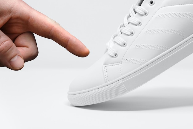 finger pointing on white sneakers shoes