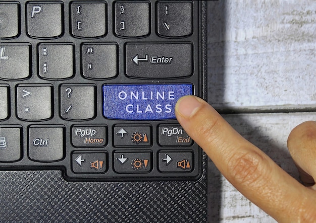 Finger pressing a blue key labeled ONLINE CLASS with symbol on a computer keyboard concept