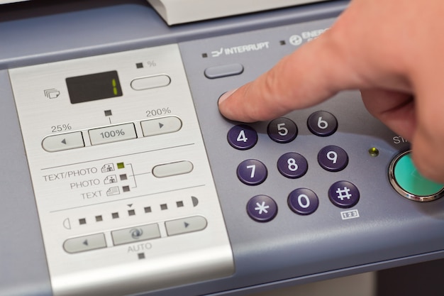 Finger pressing the buttons of the copier