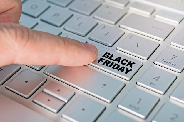 Finger pressing computer button with Black Friday sign. Internet shopping on sale on black Friday. finger presses a button on the gray keyboard.