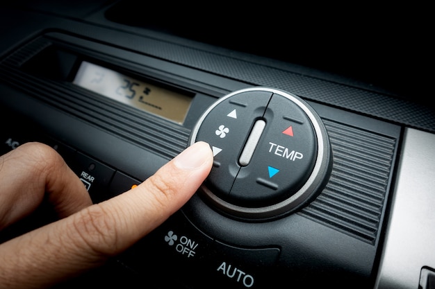 Finger pressing on fan switch of a car air conditioning system