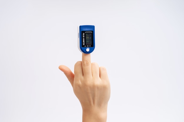 Finger pulse oximeter. On white background. The device is put on the middle finger of the hand. Refusal, health diagnostics.