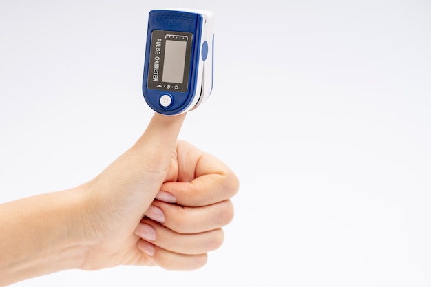 Finger pulse oximeter. On white background. The device is put on the thumb up. Health diagnostics.