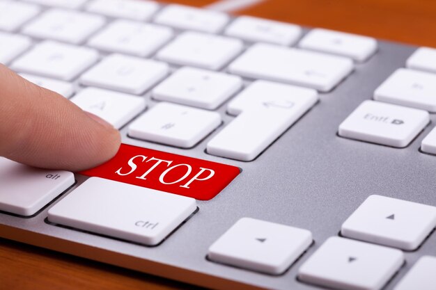 Photo finger pushing red stop button on modern keyboard. danger and web content