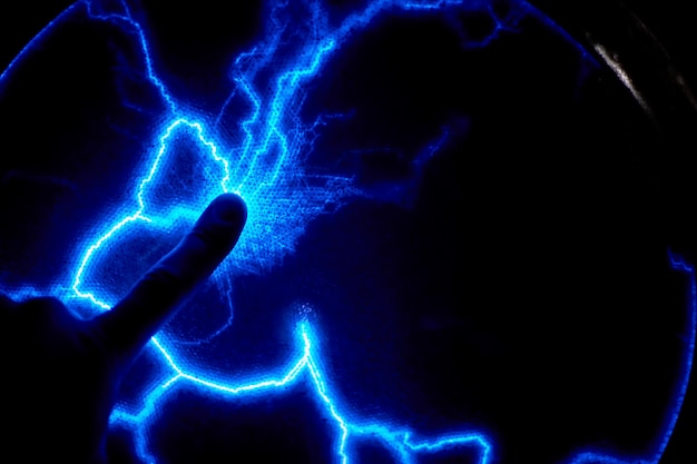 finger touch electric plasma ball on a dark background. static electricity model