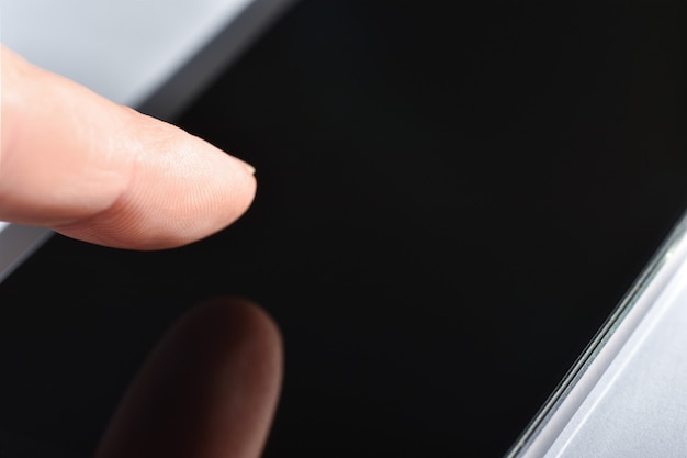 Finger touches the smartphone screen with integrated fingerprint scanner