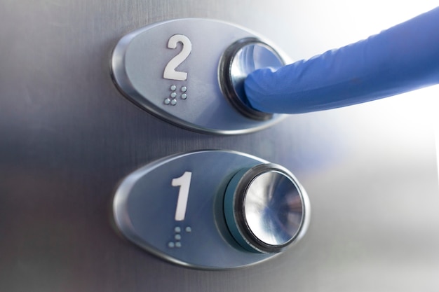 Finger with glove touching elevator button