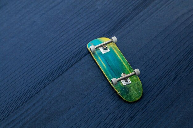 Fingerboard A small skateboard for kids and teenagers to play with hand fingers Isolated on blue wood background