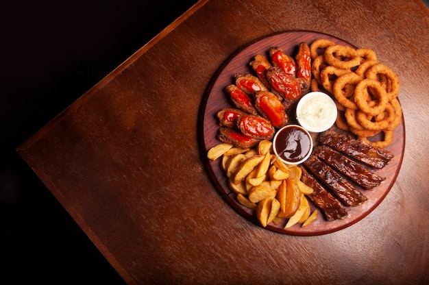 Fingerfood lisdodde met kippenvleugels in buffel uienringen barbecue varkensribbetjes en friet bovenaanzicht