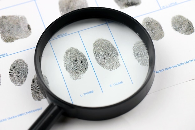 Photo fingerprints card police form on a tablet lies on office table with pen and magnifying glass