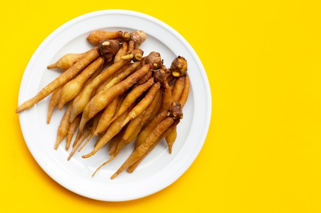 Fingerroot in white plate on yellow background.