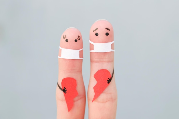 Fingers art of couple in medical mask from COVID-2019. Concept of couple holding broken heart.