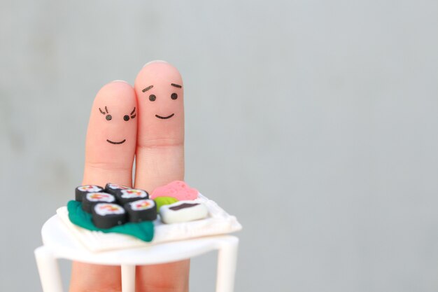 Fingers art of Happy couple. Man and woman eat sushi in cafe.