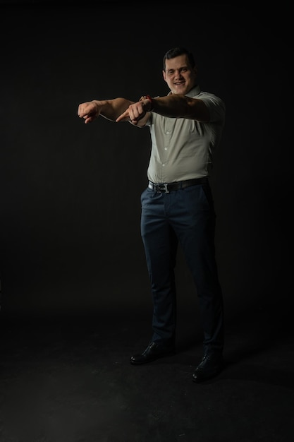 Photo fingers down holds in a grey shirt on a black background business businessman smart portrait