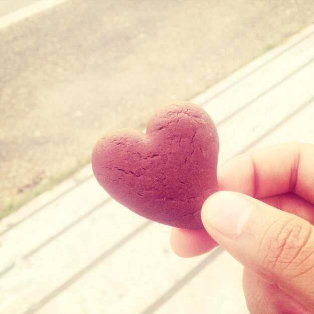 Foto le dita che tengono un biscotto a forma di cuore