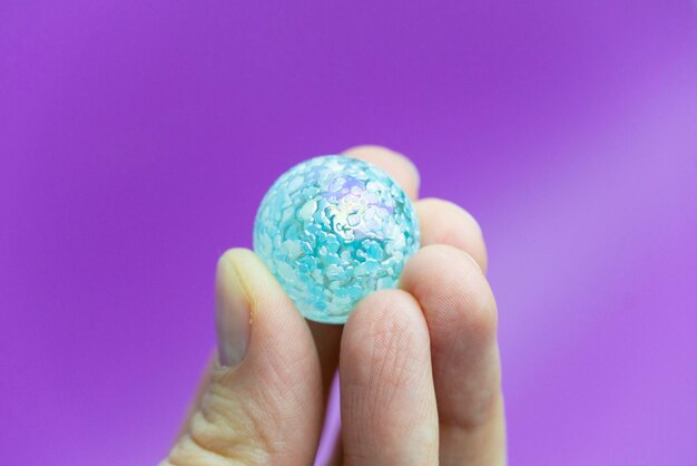 Fingers holding a little blue glass ball
