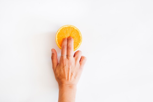 Photo fingers in an orange on a white background