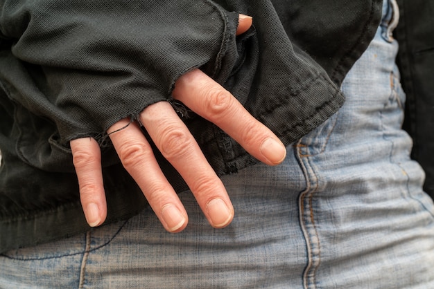 Fingers sticking out of the poor man's pocket with holes. Empty pocket.